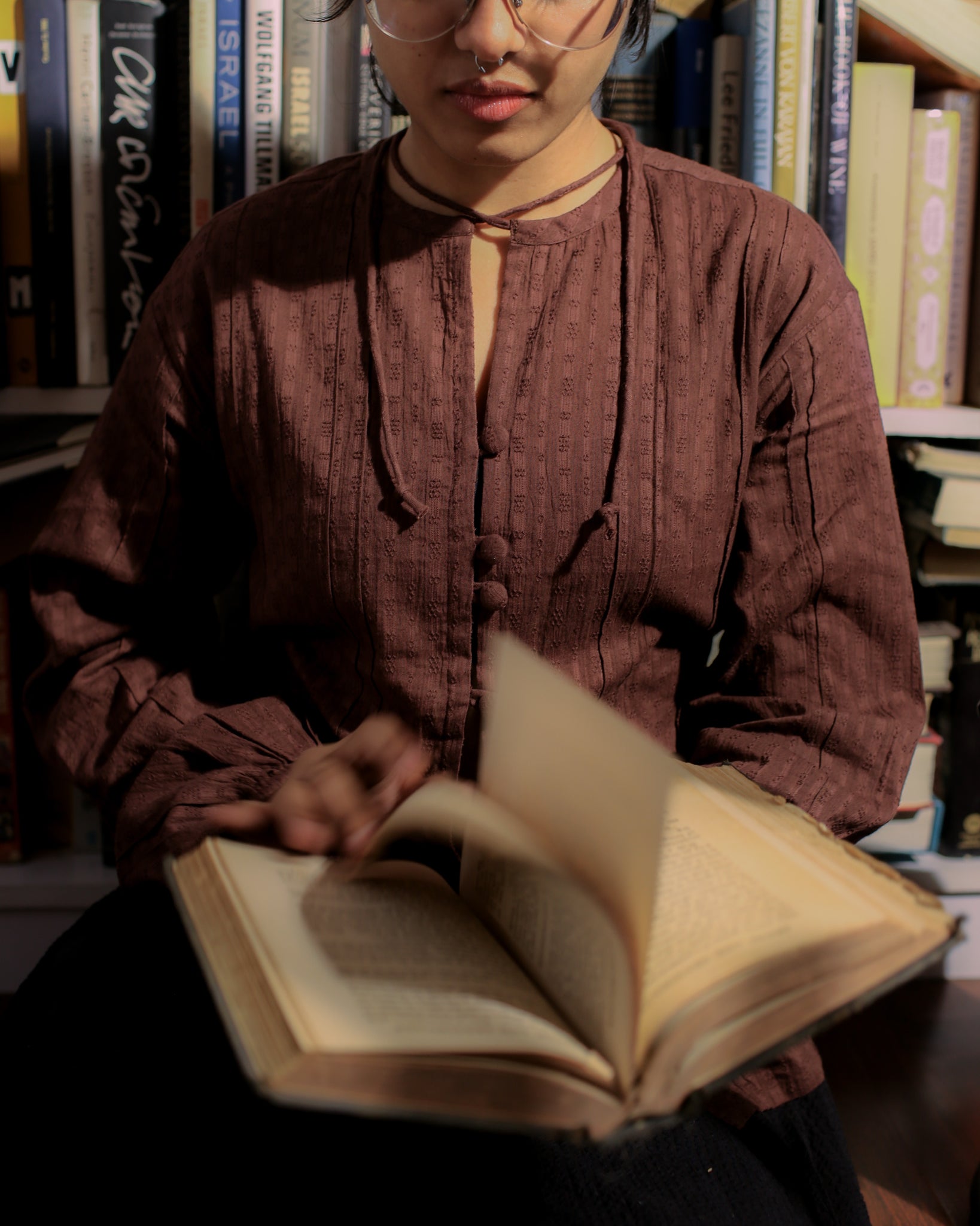 Chocolate brown dobby blouse with front pintucks and fabric buttons, styled for a vintage reading moment.