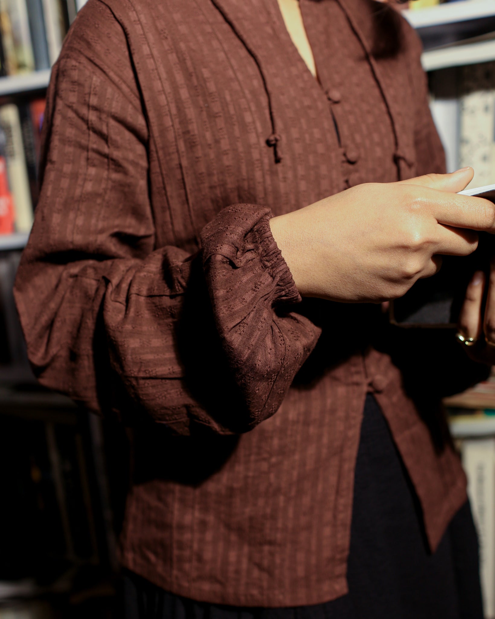 Detailed shot of self-textured dobby sleeve with soft elastic cuff and fabric pintucks, styled with vintage book.