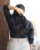 Rear view of black structured cotton satin shirt, showing long sleeves and high back neckline.