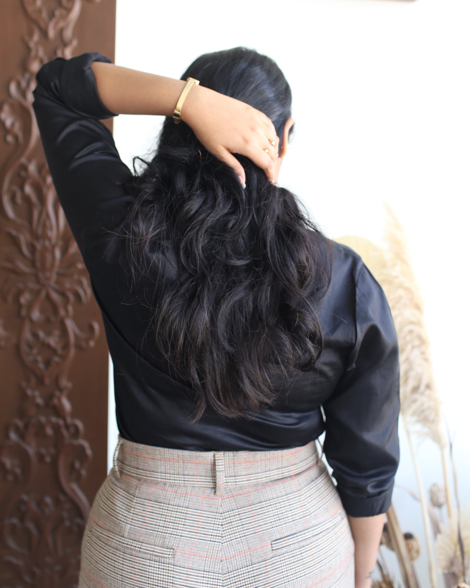 Rear view of black structured cotton satin shirt, showing long sleeves and high back neckline.