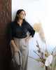 young woman in sculpted black shirt with curved hem and long sleeves, evoking classic power dressing.