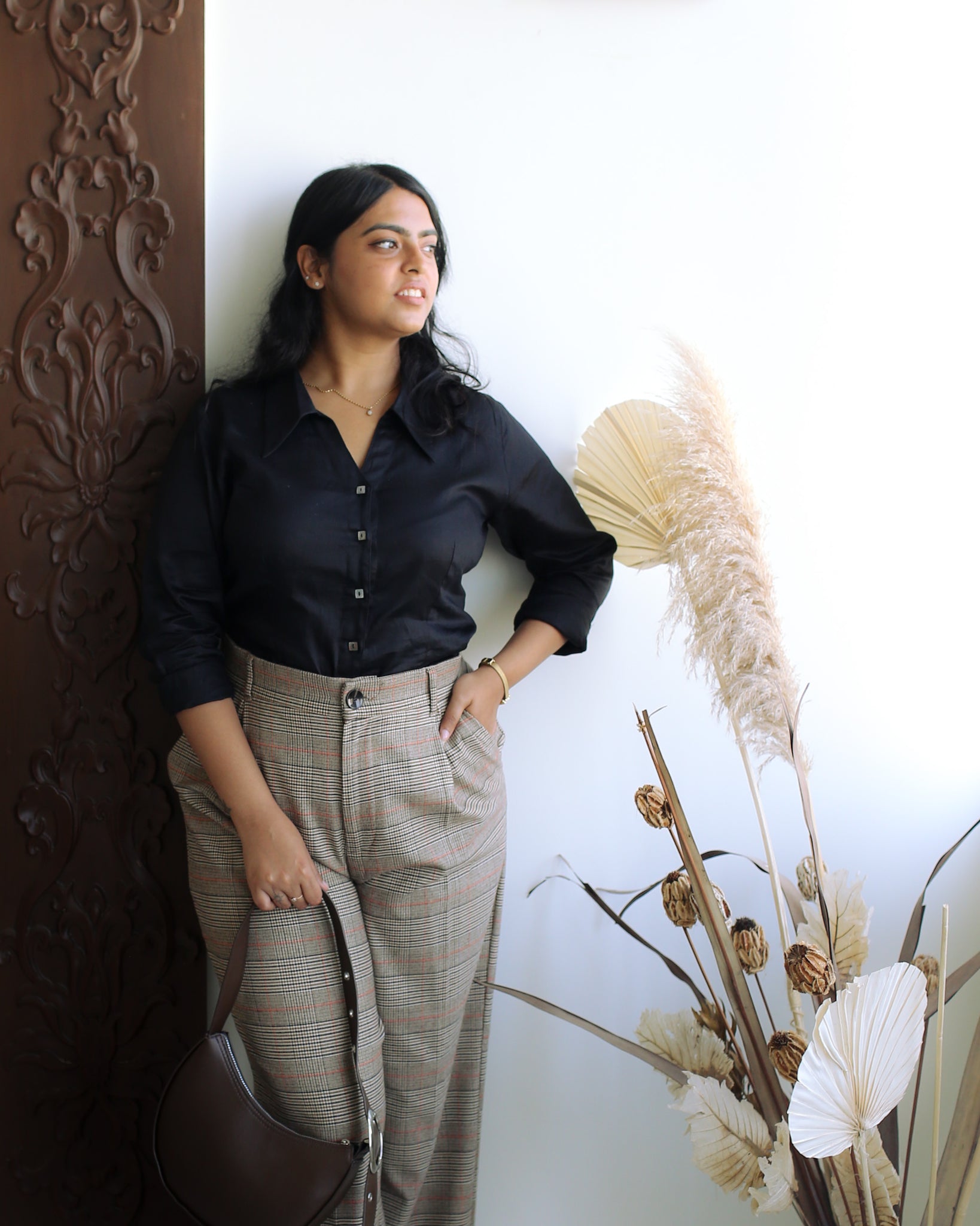 young woman in sculpted black shirt with curved hem and long sleeves, evoking classic power dressing.