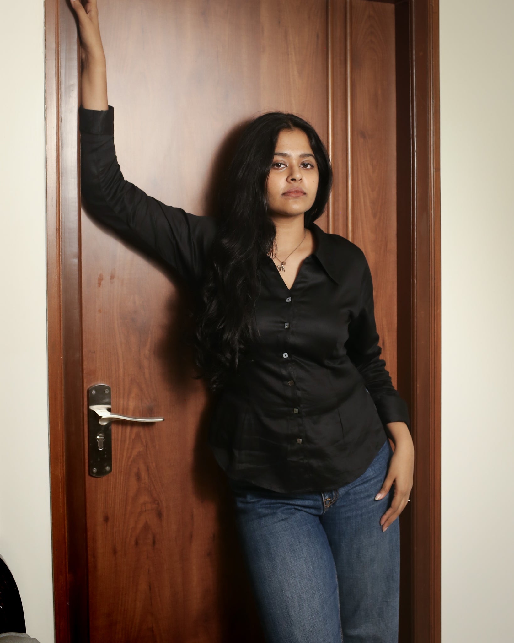 Woman showcasing the tailored waist fit and soft sheen of black satin cotton shirt