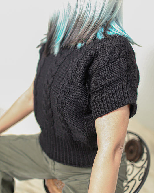 Boxy hand-knitted black wool sweater in 100% pure wool with braided knit detailing on the front.