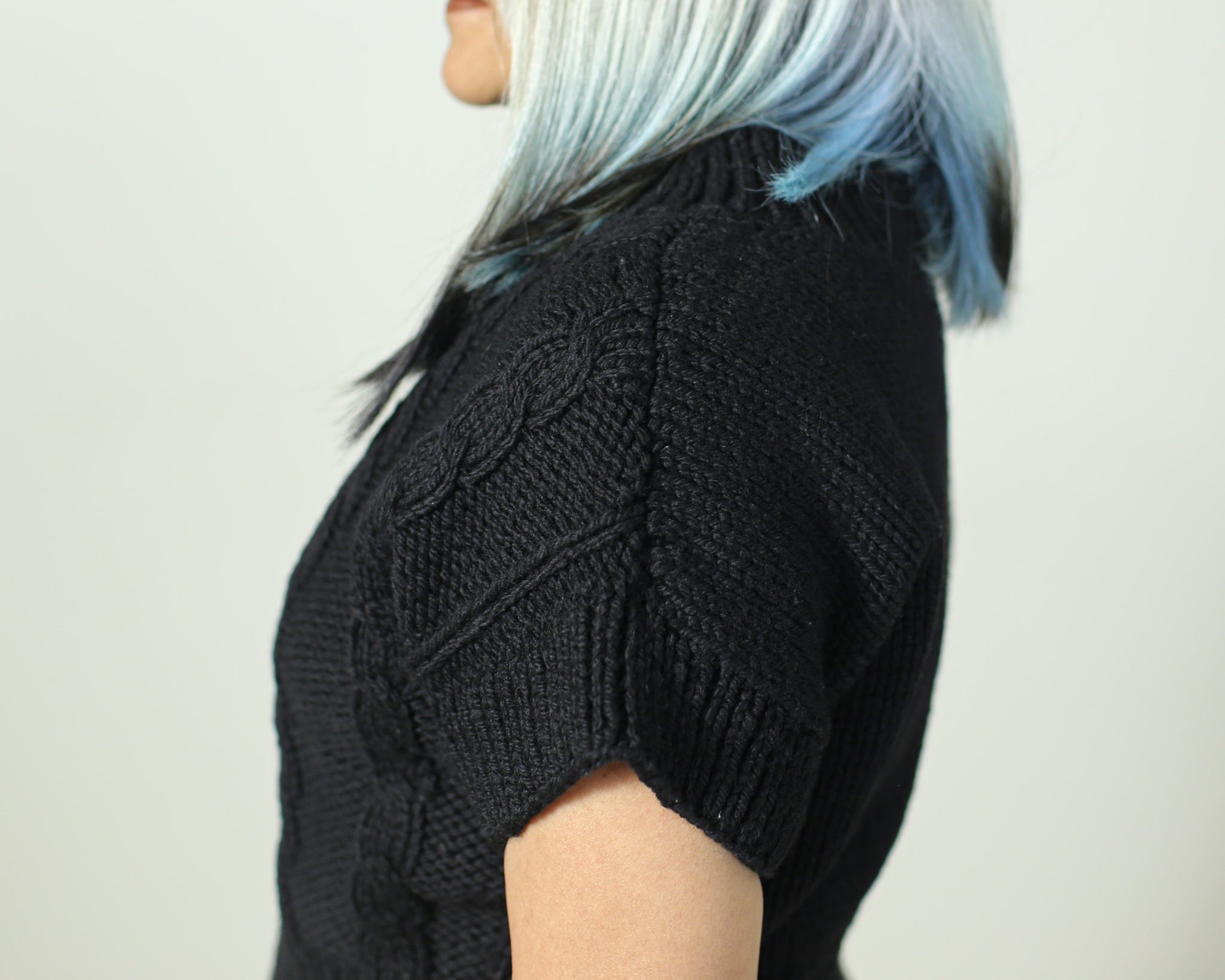 Side view of a black wool sweater in 100% pure wool with armhole border for a structured fit.