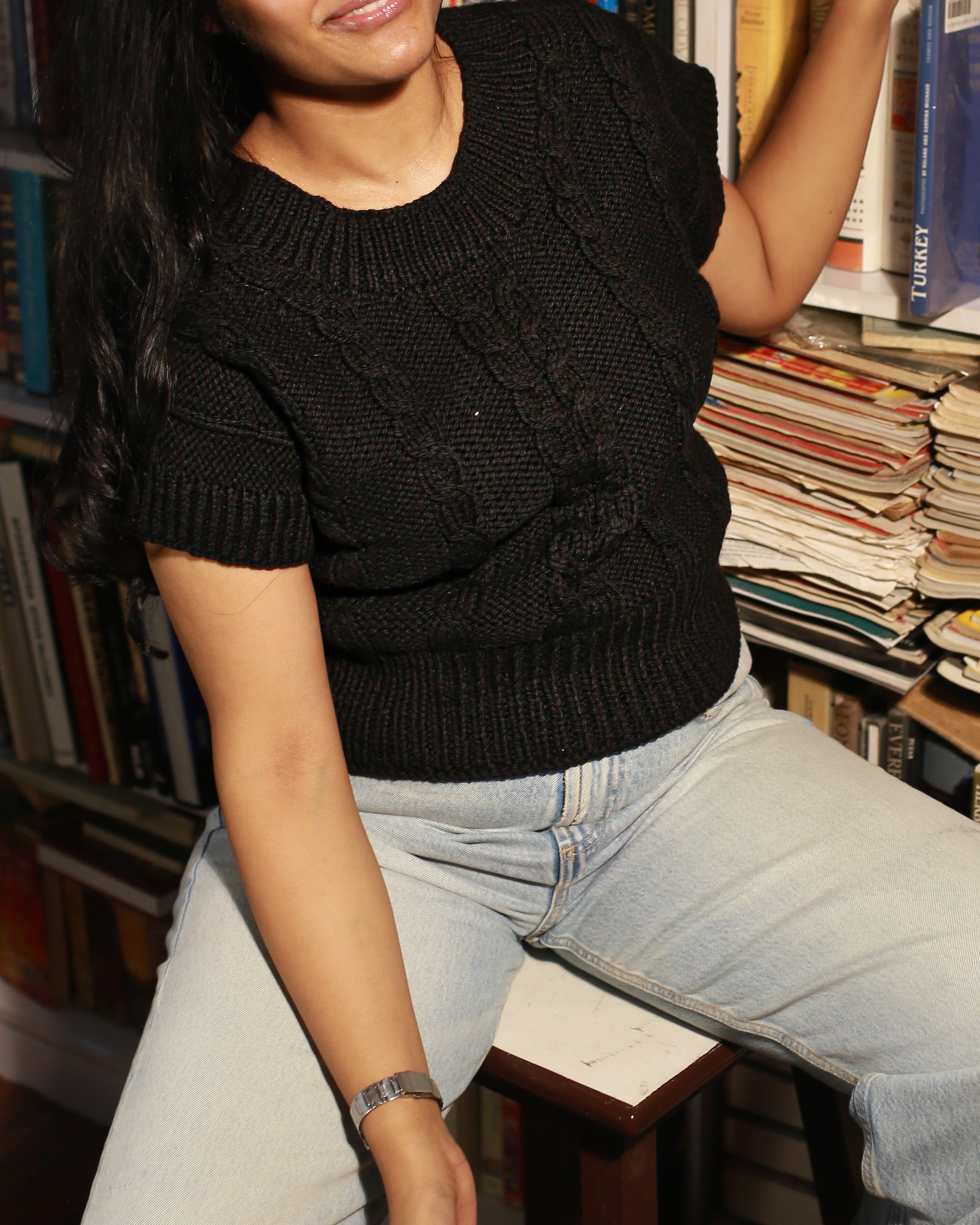 Model styling a black wool sweater in 100% pure wool with jeans for a casual winter look.