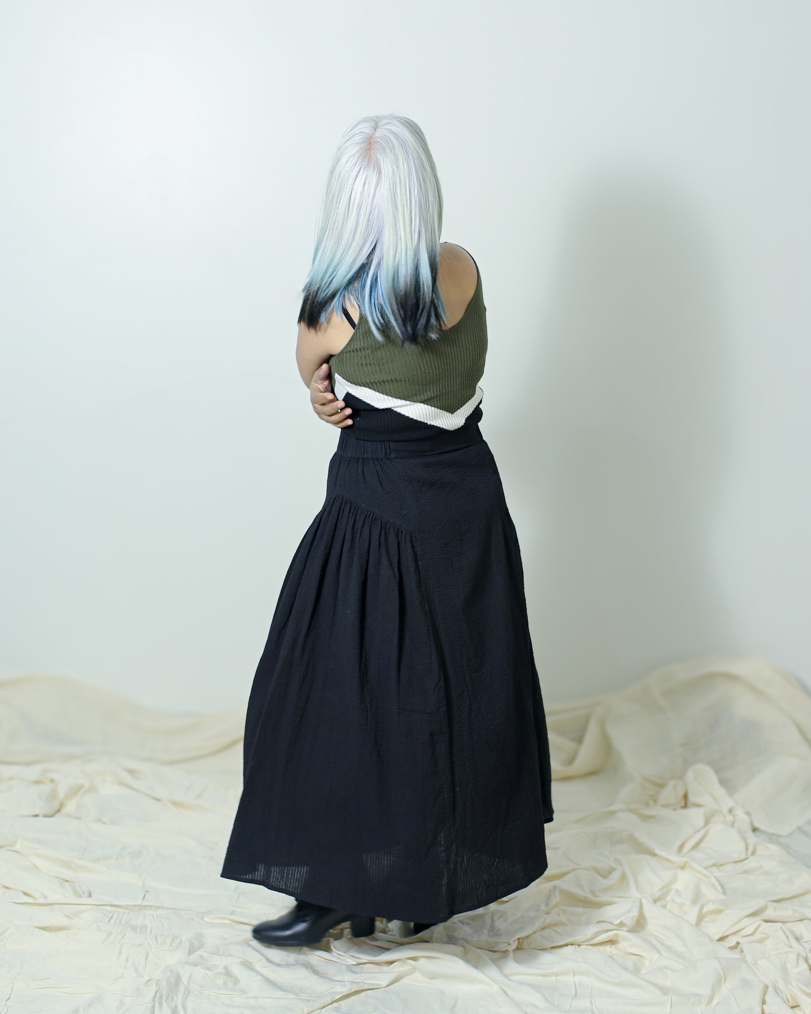 Model wearing a black cotton skirt styled with a fitted top and boots.