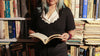Black wool scallop neck sweater in 100% pure wool styled casually with jeans in a cozy library setting.