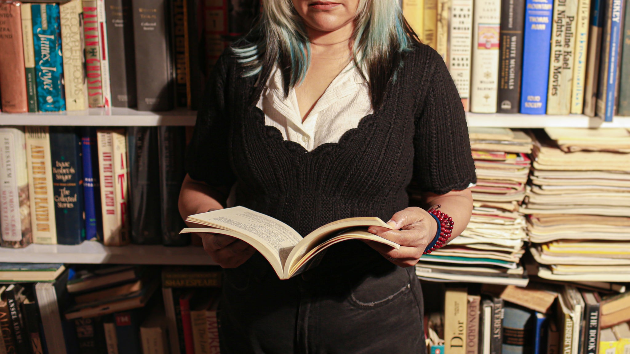 Black wool scallop neck sweater in 100% pure wool styled casually with jeans in a cozy library setting.