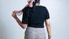 Back view of a black scallop neck sweater in 100% pure wool styled with high-waisted trousers.