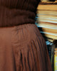 close-up of the side gather panel of midi skirt in brown having elasticated waistband.