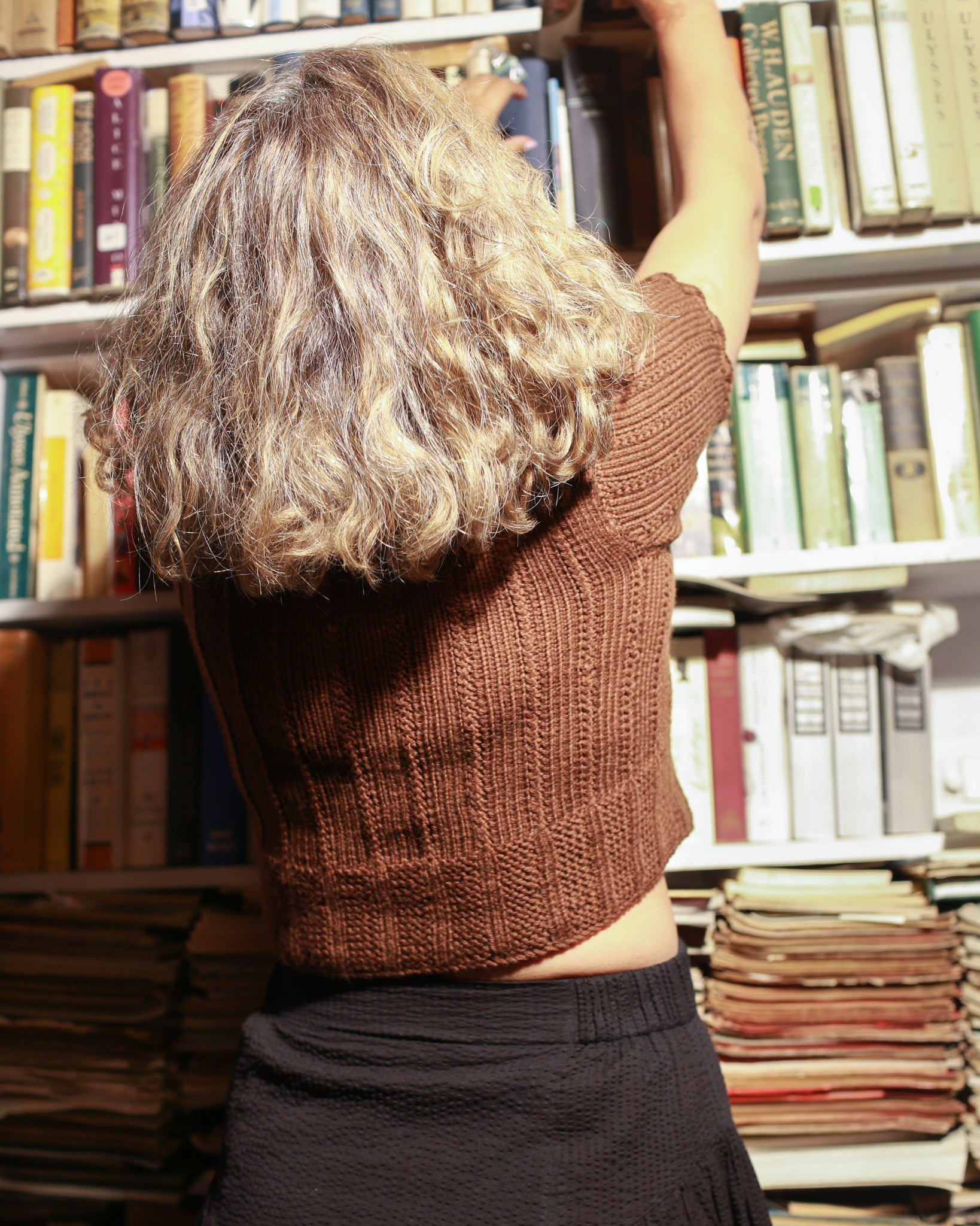 Back view of a black scallop neck sweater  made by 100% pure wool styled with black skirt.