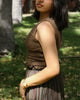 Woman in sleeveless cinch top walking in shade, ideal summer wear with earthy textures.
