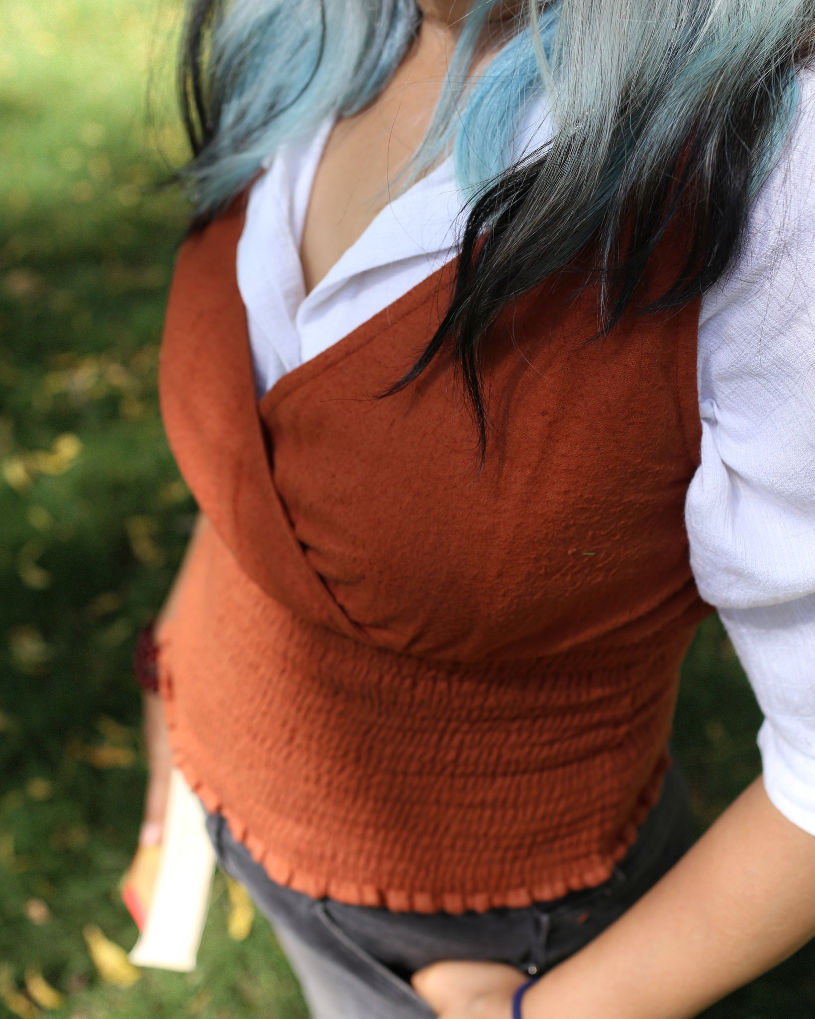 Burnt ochre cotton cinch top styled over a white shirt, highlighting rustic color and layered versatility.