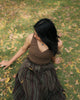 Sleeveless moss green V-neck top styled with ethnic skirt in a lush outdoor park setting