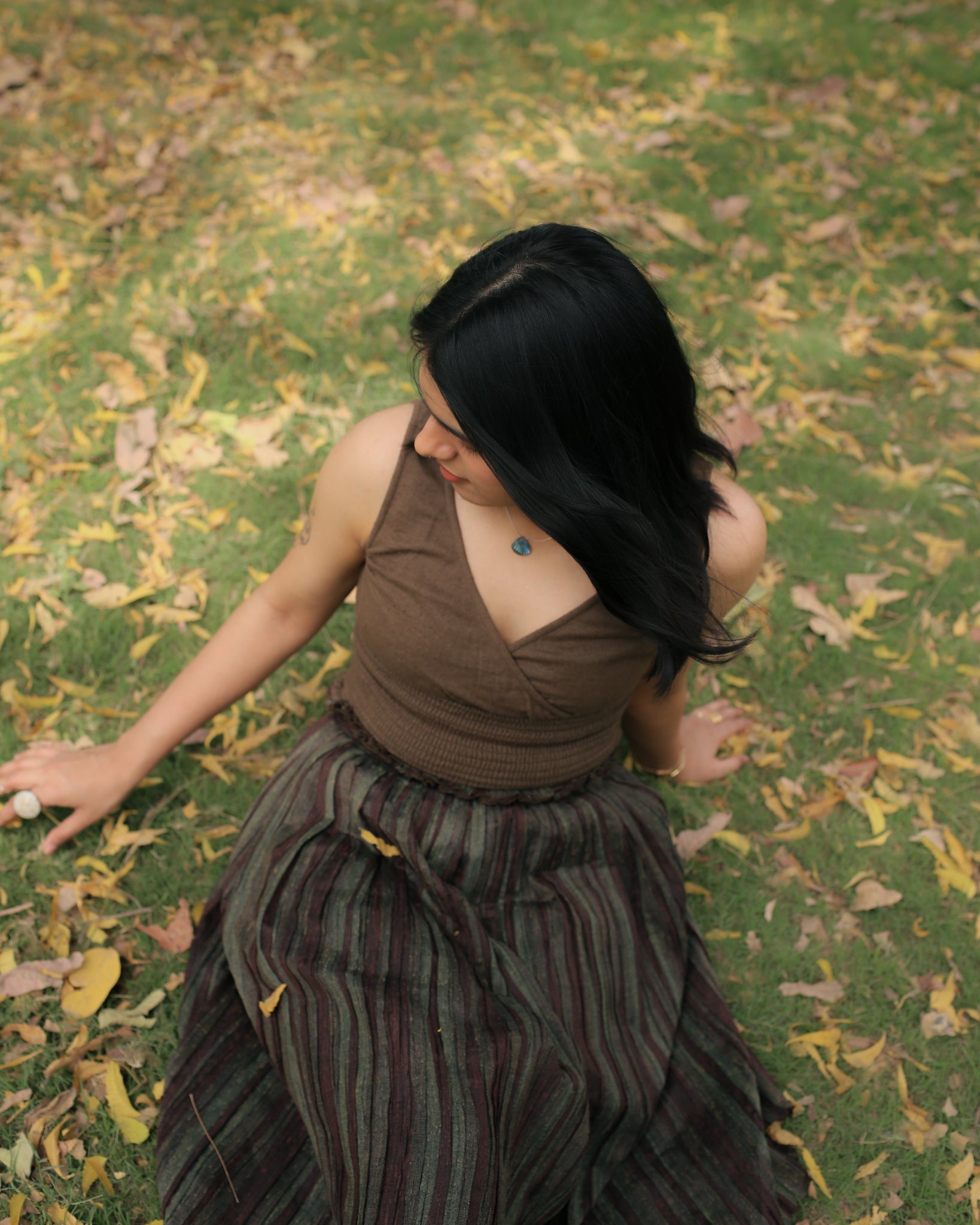 Sleeveless moss green V-neck top styled with ethnic skirt in a lush outdoor park setting