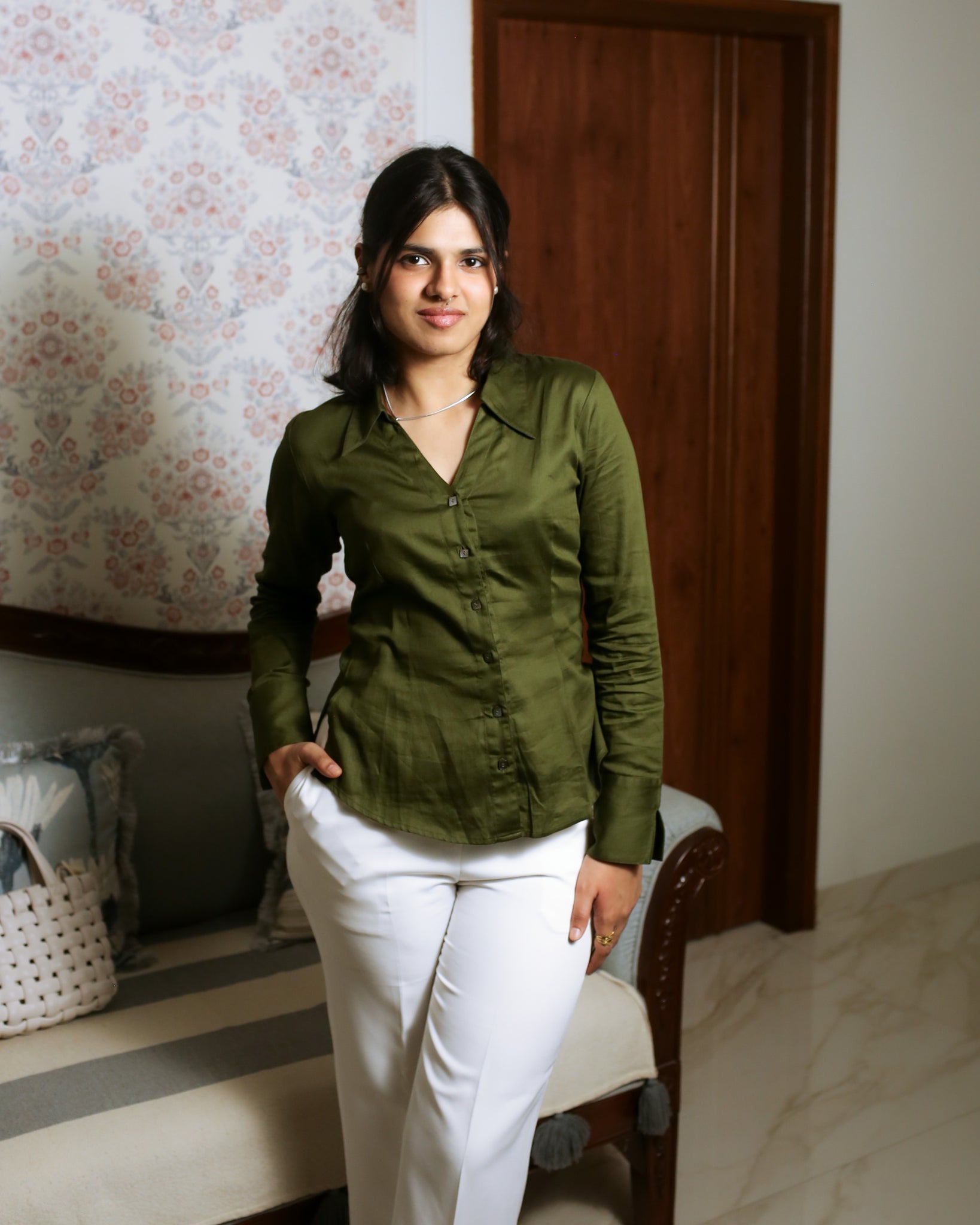 Woman styled in olive green satin cotton shirt with white trousers for modern office aesthetic.
