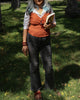 Burnt ochre sleeveless top layered with shirt and paired with grey pants, holding a book outdoors.