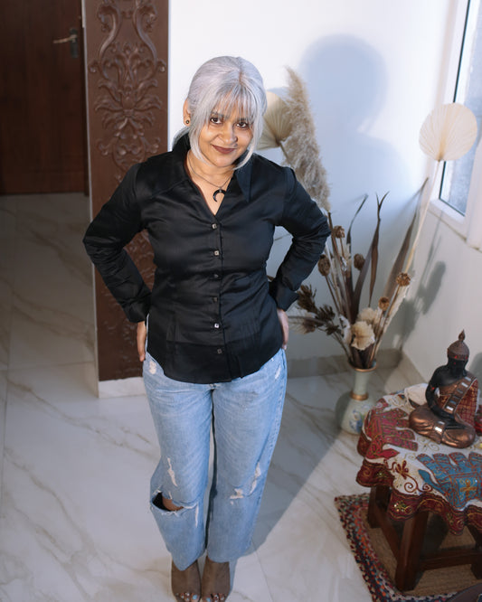 Woman wearing black satin cotton fitted shirt with sharp collar, styled with blue jeans for everyday ease.