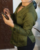 Woman in motion wearing olive green structured shirt with satin sheen, highlighting sharp collar and fit.