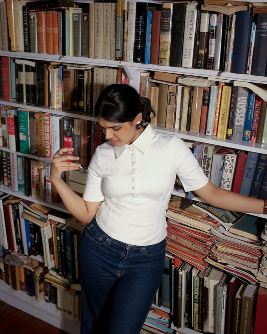Ivory white polo top worn for a casual workwear look in indoor lighting