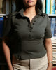 close-up detail of a woman wearing a dark green polo shirt in front of bookshelves
