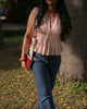Side view of sleeveless cotton pleated top with wooden buttons and soft peplum flare, lightweight summer wear