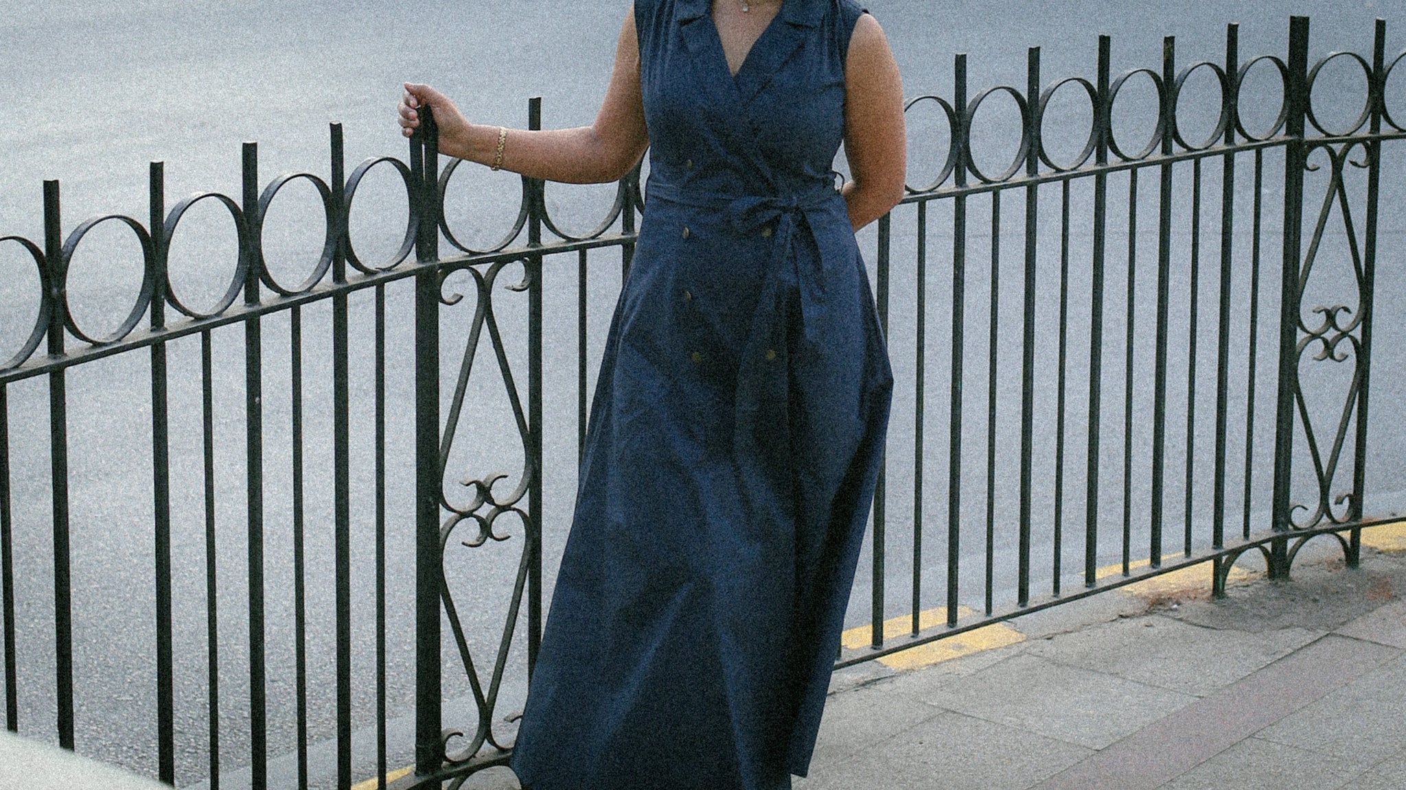 Woman wearing midnight blue belted trench dress with wrap front and A‑line silhouette on city street