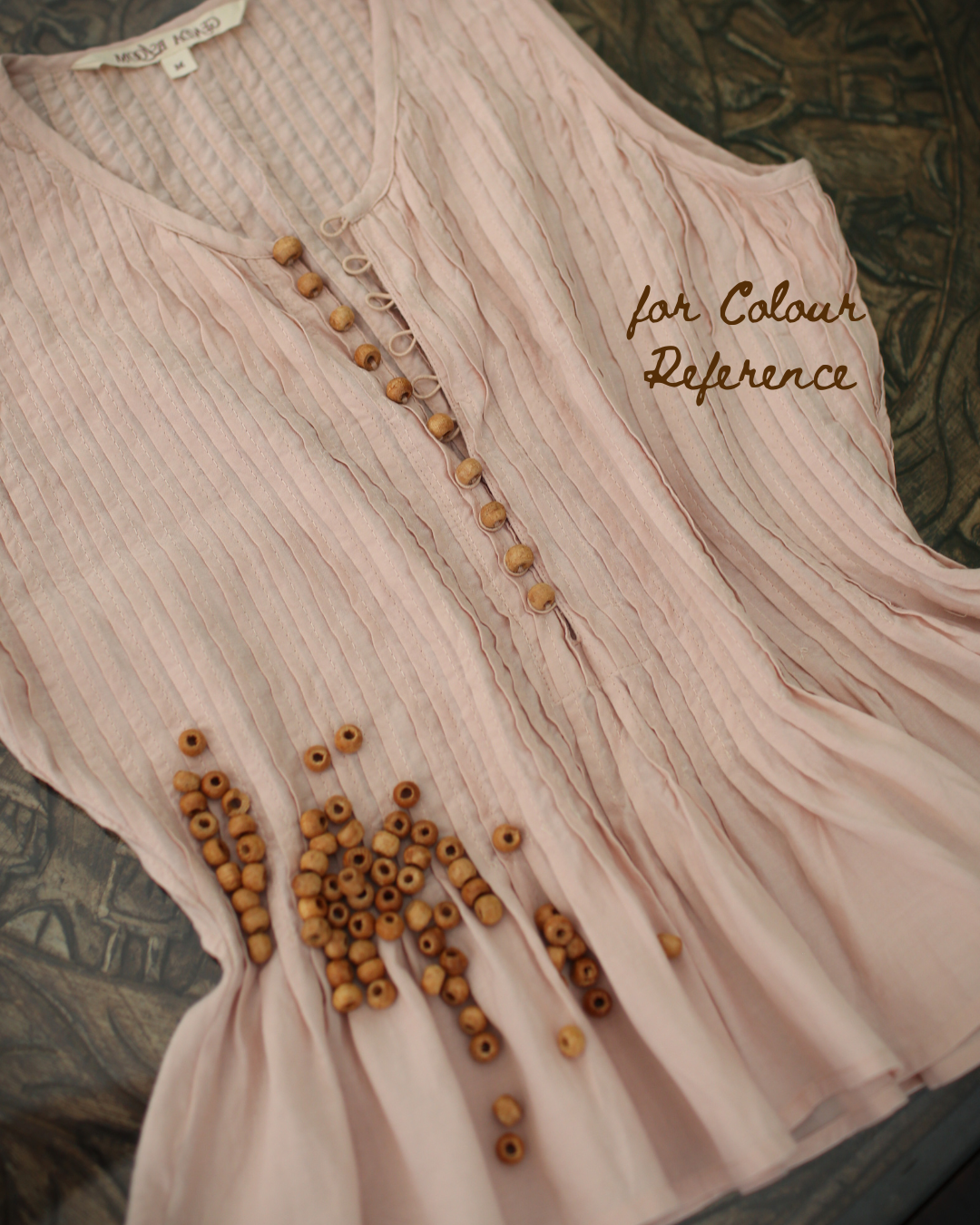 Close-up of textured cotton fabric with fine pleats and wooden button detailing, soft flowy finish, for colour reference
